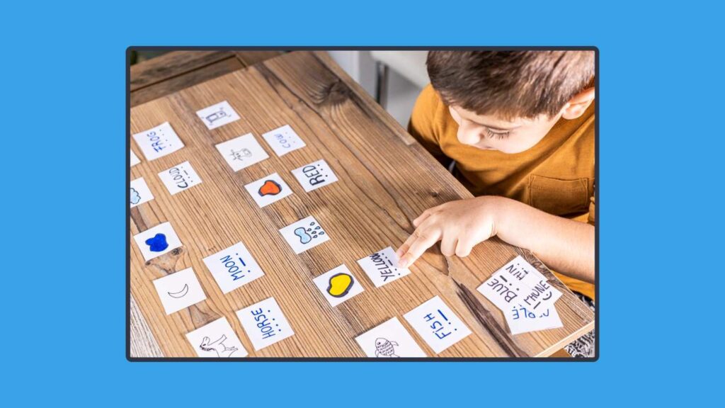 A photo of a child sitting on a table with learning cards on it.